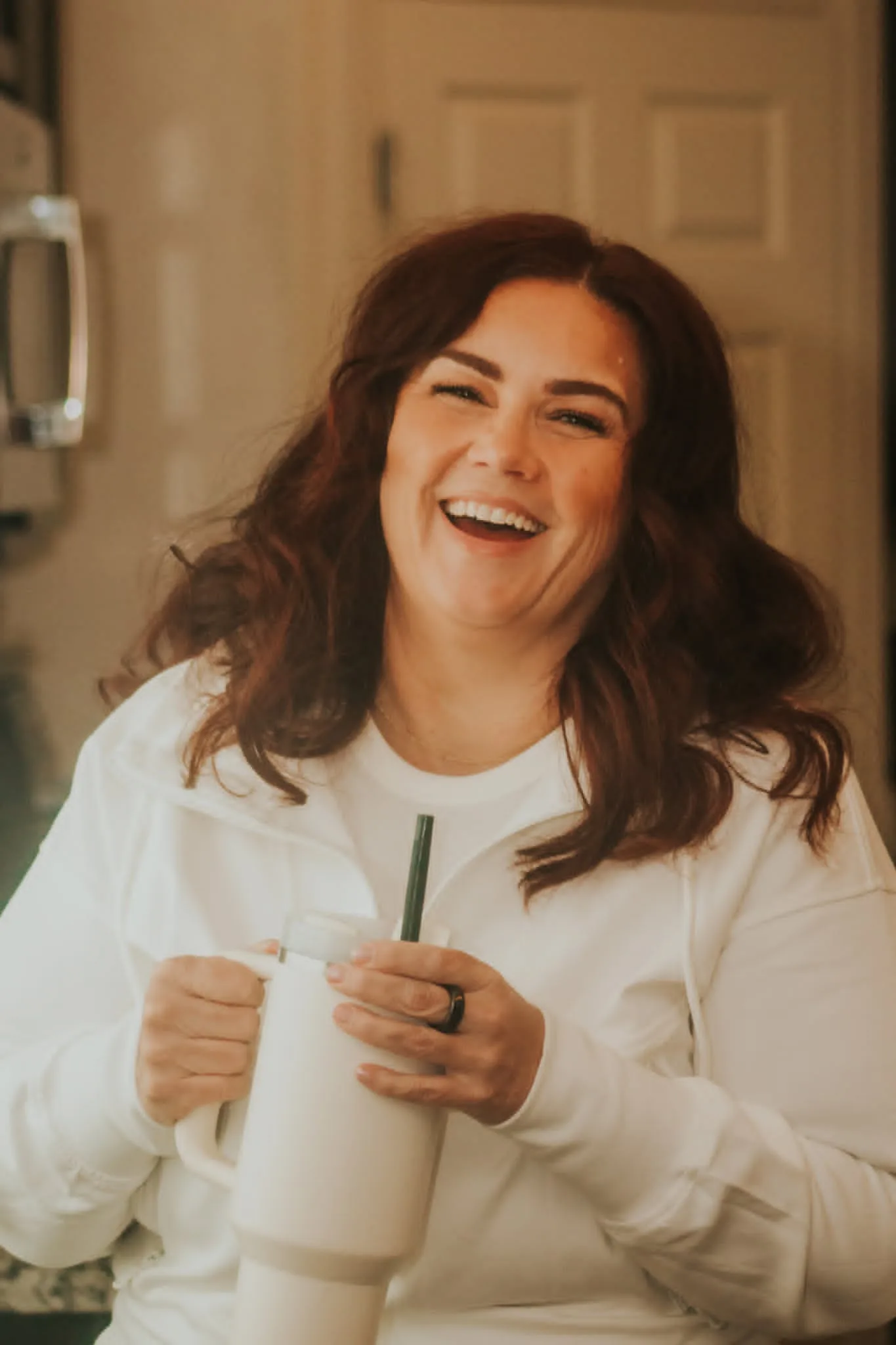 Melissa Anne laughing and holding a tumbler